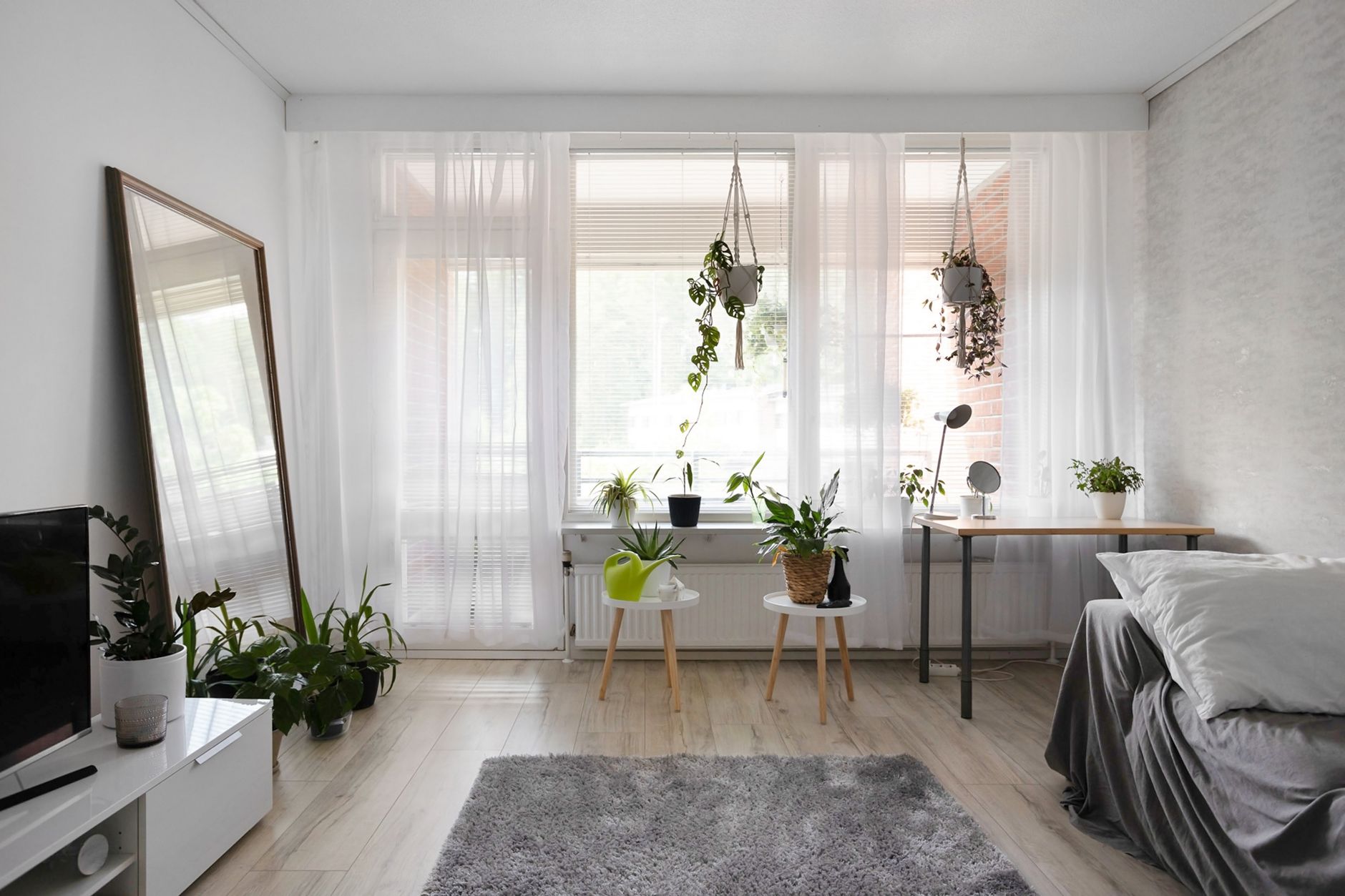 Small apartment living room with large leaning floor mirror reflecting natural light