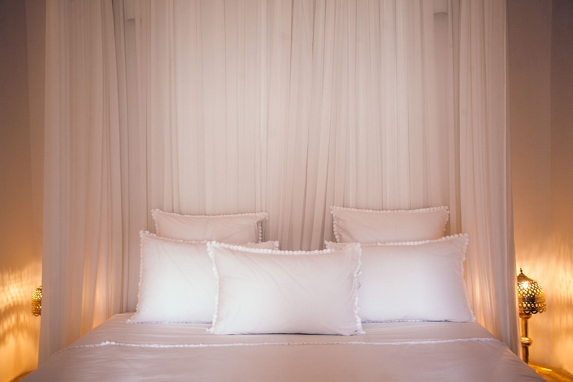 White canopy curtains creating private bedroom zone in studio apartment